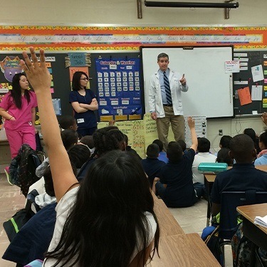 Doctor Jay and two dental team members presenting at Springhill Lake Elementary School