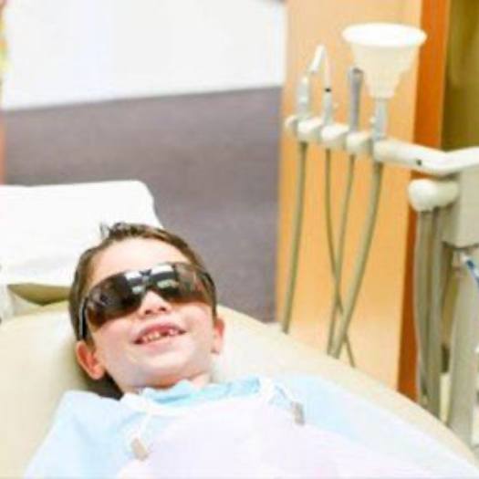 Young boy wearing sunglasses and smiling in dental chair