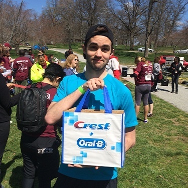 Young man holding a Crest and Oral B gift bag at the Oral Cancer Walk