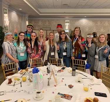 Team in 70s clothes for themed continuing education meeting