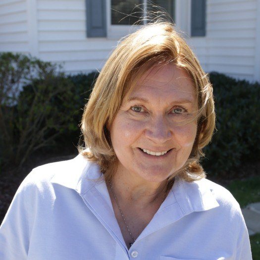 Woman in white buttoned shirt grinning outdoors