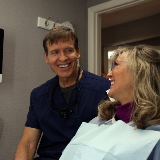 Dentist smiling at a patient in the dental chair