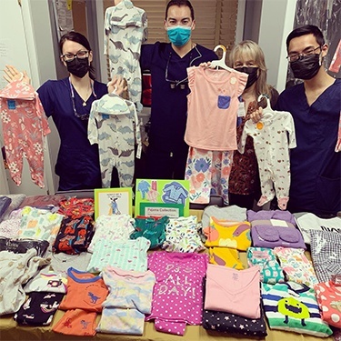 Dental team members holding pajamas for small children