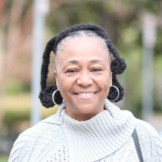 Woman in gray sweater smiling outdoors