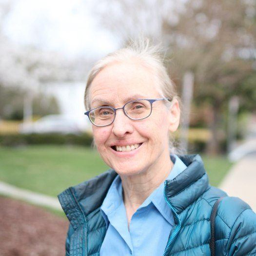 Woman in blue puffy jacket smiling outdoors