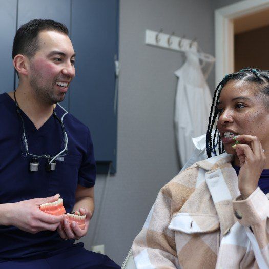 Dentist holding models of teeth while talking to a patient