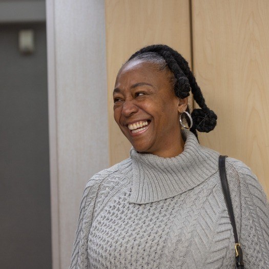 Woman in gray sweater smiling after replacing missing teeth