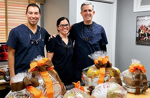 Three dentists next to table with wrapped Thanksgiving food