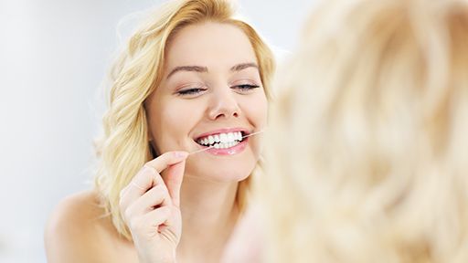 Blonde woman flossing her teeth