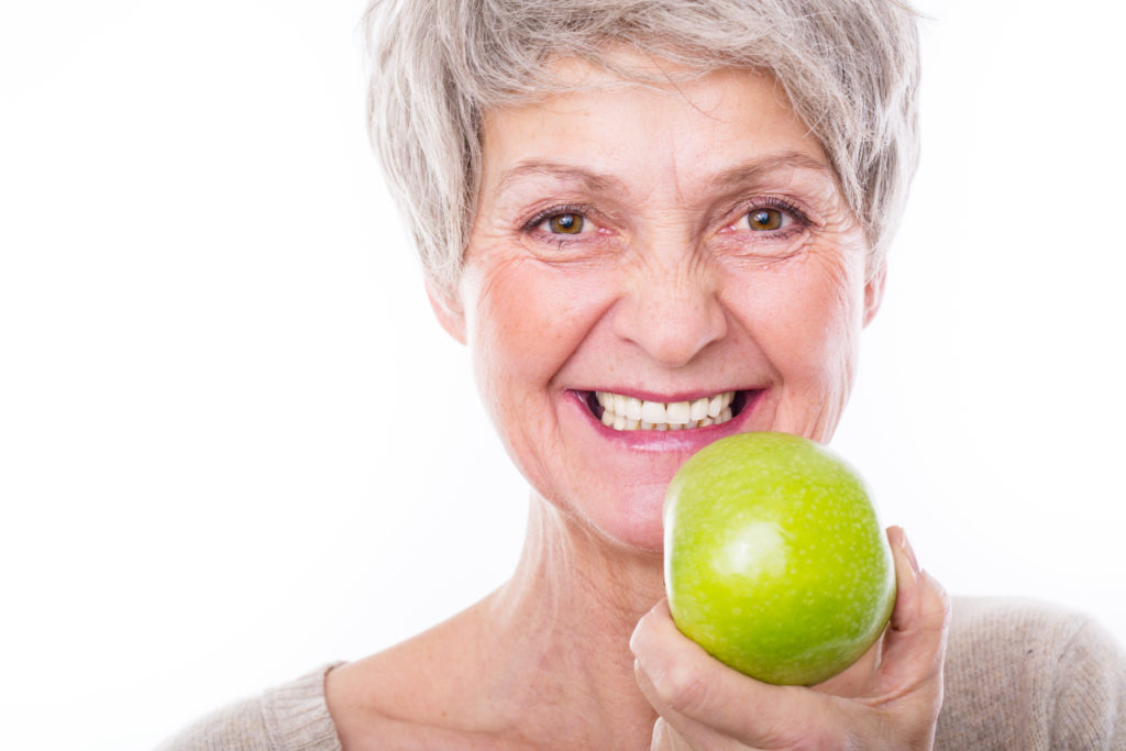 Smiling senior woman holding an apple