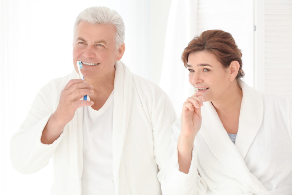Older man and woman brushing teeth together