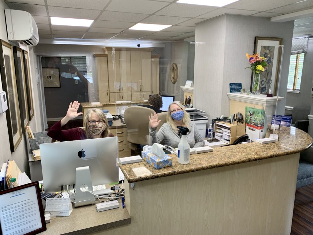 Two dental team members at front desk waring face masks