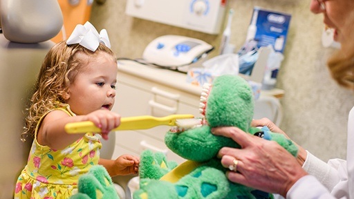 Little girl practicing tooth brushing in the dental office